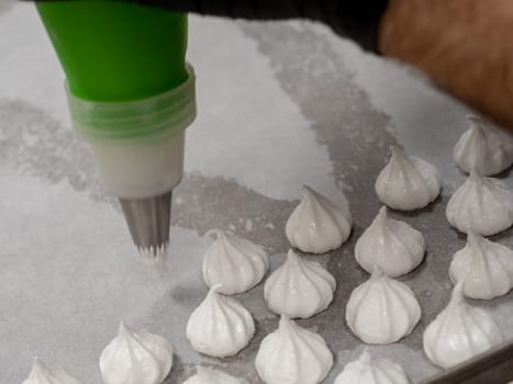 pastry chef baker artisan making white swirl and twirl meringue cones with piping bag filled with egg white cream and sugar to bake for sweet preparation 4k footage