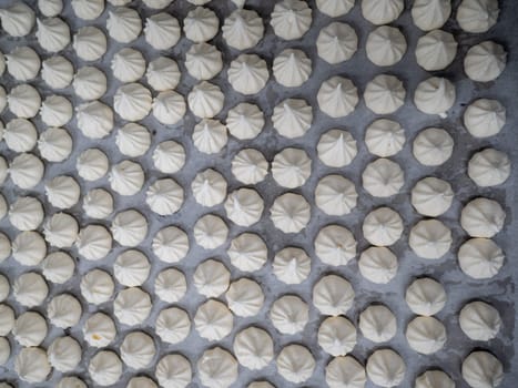 pastry chef baker artisan making white swirl and twirl meringue cones with piping bag filled with egg cream and sugar to bake for sweet preparation