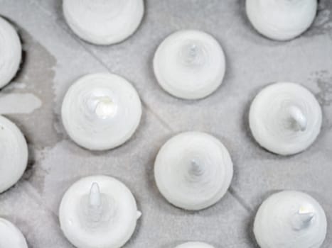 pastry chef baker artisan making white swirl and twirl meringue cones with piping bag filled with egg cream and sugar to bake for sweet preparation