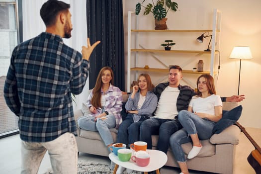 Playing game with using body language and poses. Group of friends have party indoors together.