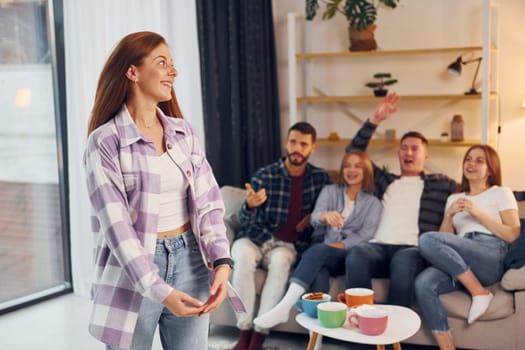 Playing game with using body language and poses. Group of friends have party indoors together.