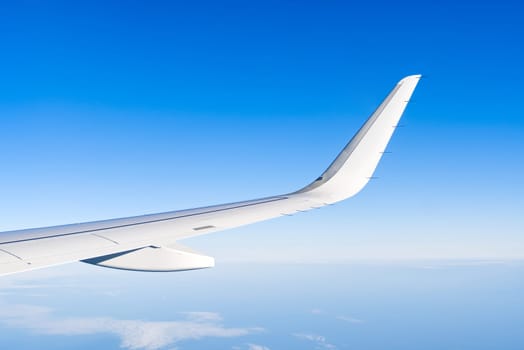 Airplain wing view thrue window in the sky. Clouds and sky as seen through porthole of an aircraft with airplane's wing