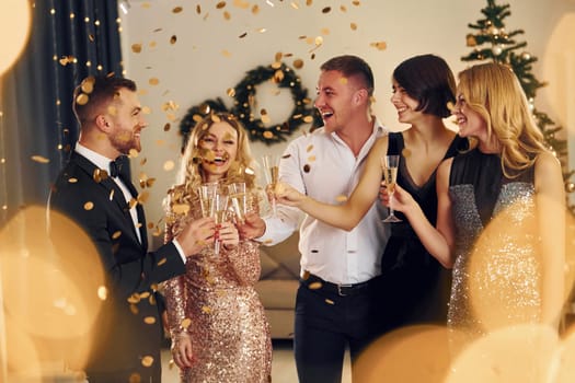 Cheering with champagne. Group of people have a new year party indoors together.
