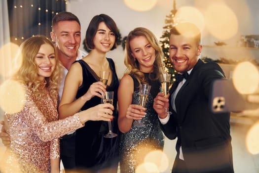 Making selfie. Group of people have a new year party indoors together.