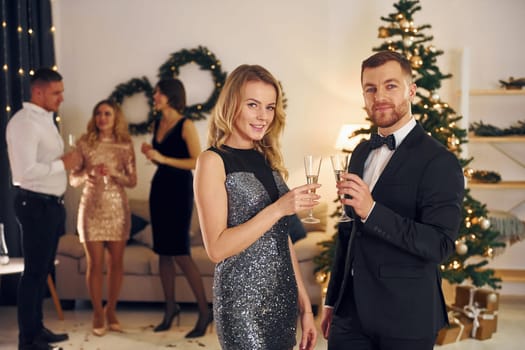 Beautiful couple. Group of people have a new year party indoors together.