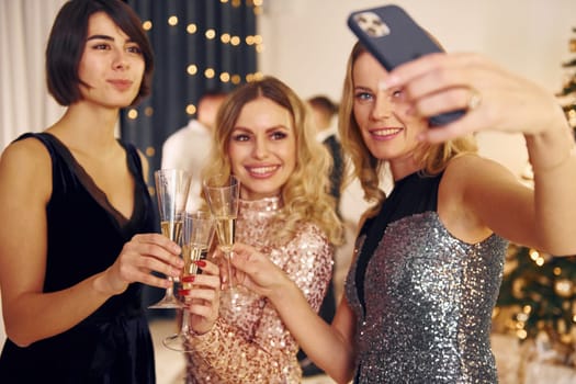 With glasses of drink. Group of people have a new year party indoors together.