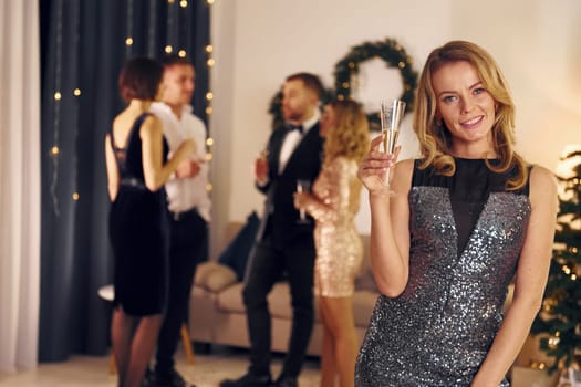 Woman is in the front of her friends. Group of people have a new year party indoors together.