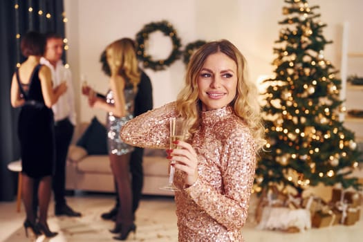 Woman standing in front of her friends. Group of people have a new year party indoors together.