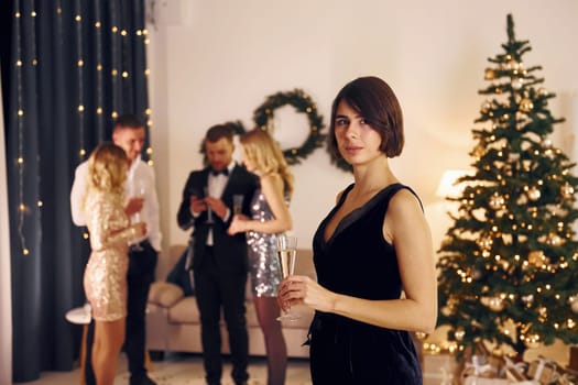 Woman standing in front of her friends. Group of people have a new year party indoors together.