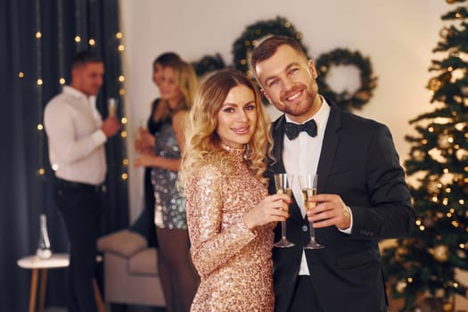 Young couple. Group of people have a new year party indoors together.