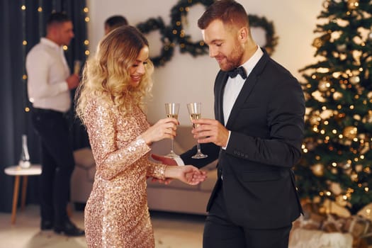 Young couple. Group of people have a new year party indoors together.