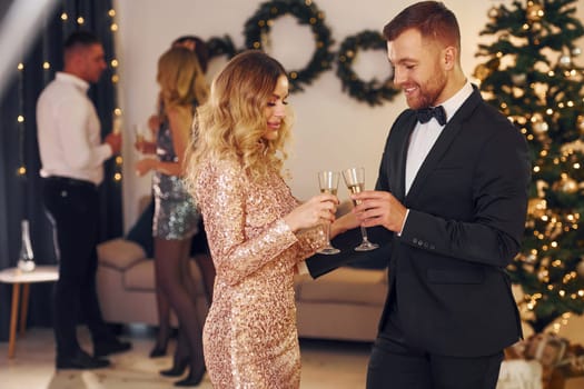 Young couple. Group of people have a new year party indoors together.