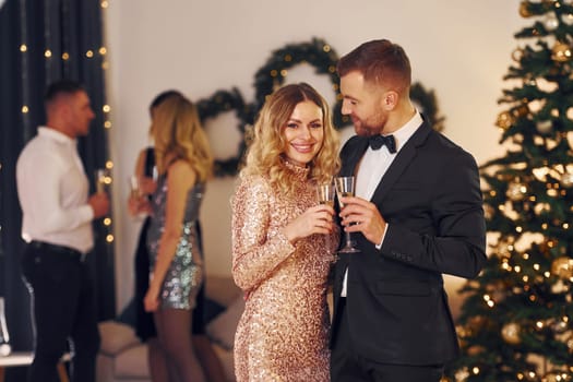 Young couple. Group of people have a new year party indoors together.