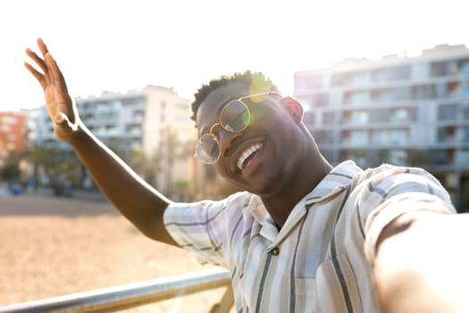 African American man taking selfie outdoors. Smiling, happy, African american Black male with glasses looking at camera waving hello. Vacation concept.