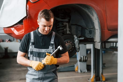 Professional service. Man in uniform is working in the auto service.