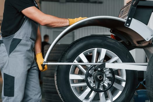 Fixing the tire. Man in uniform is working in the auto service.