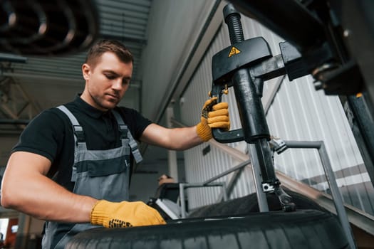 Strong hands. Man in uniform is working in the auto service.