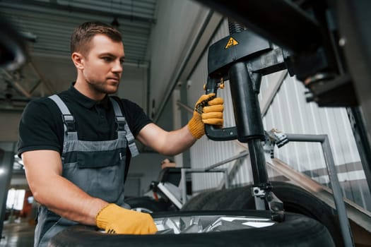 Strong hands. Man in uniform is working in the auto service.