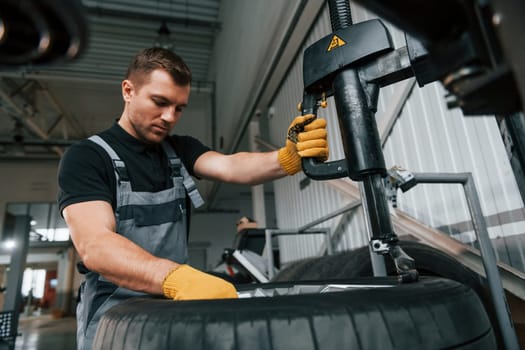 Strong hands. Man in uniform is working in the auto service.