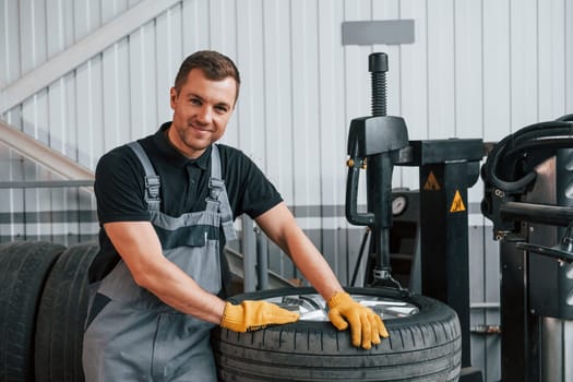 Broken wheel. Man in uniform is working in the auto service.