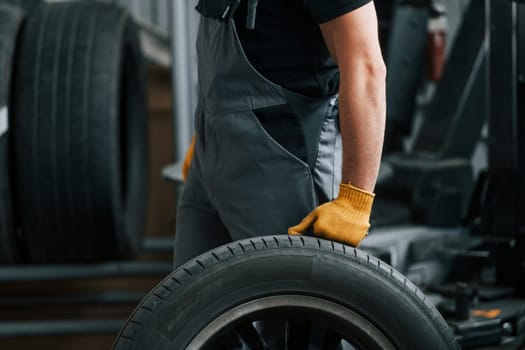 Replacement of the old tire. Man in uniform is working in the auto service.