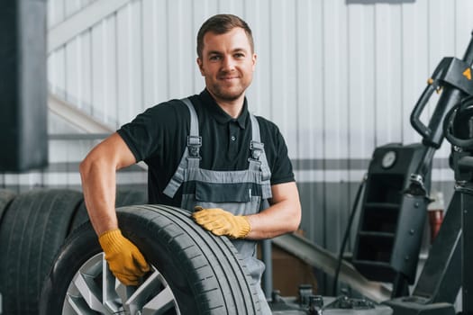 In uniform. Man is working in the auto service.