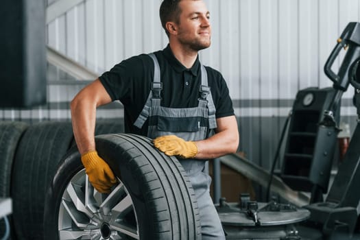 In uniform. Man is working in the auto service.