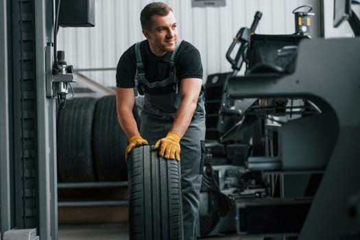 In uniform. Man is working in the auto service.