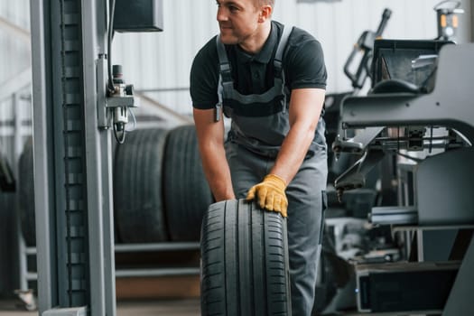 Front view. Man in uniform is working in the auto service.