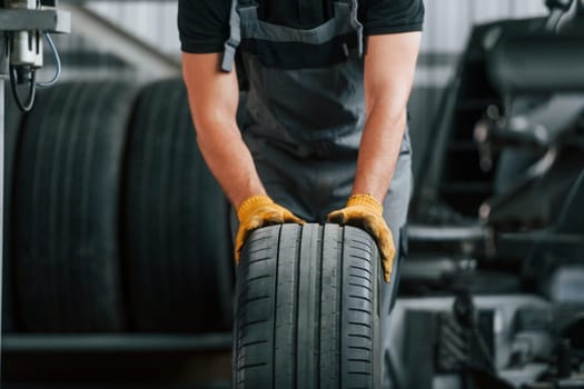 Front view. Man in uniform is working in the auto service.