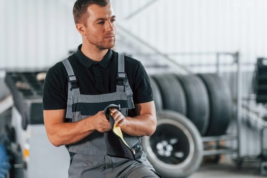 Ready to solve the problem. Man in uniform is working in the auto service.