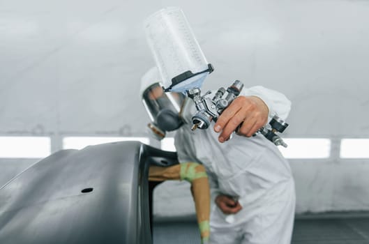 Ready for the painting. Man in uniform is working in the auto service.