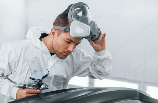 Working with car surface. Man in uniform is working in the auto service.