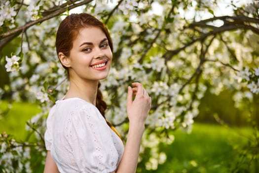 joyful woman posing standing next to a flowering tree enjoying nature. High quality photo