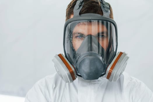 Portrait of man in the protective mask. Worker in uniform is in the auto service.