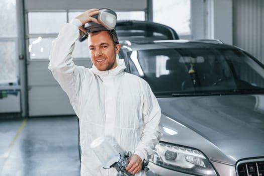 Job is done. Man in uniform is working in the auto service.