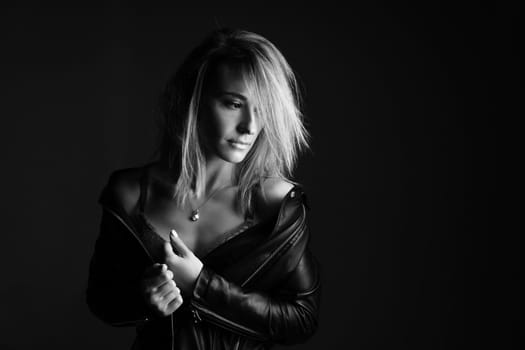 Portrait of a woman in a leather jacket and lingerie, black and white photo. Beautiful caucasian woman of nationality sensitive portrait on black background