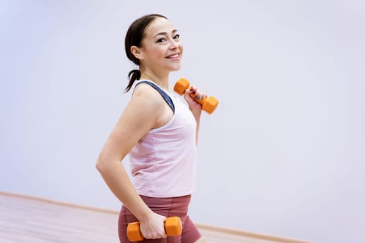 Portrait of a European sports woman in sportswear with dumbbells in her hands. Slimming and health concept