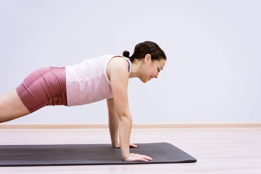 happy woman doing sports at home against wall background, healthy lifestyle concept