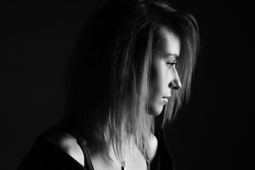 Portrait of a woman in a leather jacket and lingerie, black and white photo. Beautiful caucasian woman of nationality sensitive portrait on black background