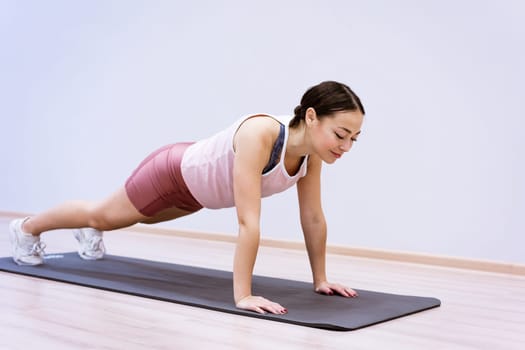 happy woman doing sports at home against wall background, healthy lifestyle concept