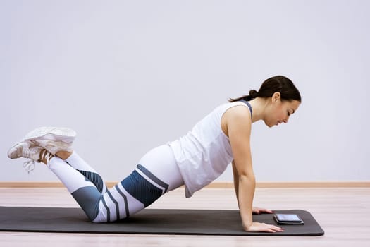 A woman goes in for sports watching an online video from a tablet. Fitness class concept ss workout without leaving home