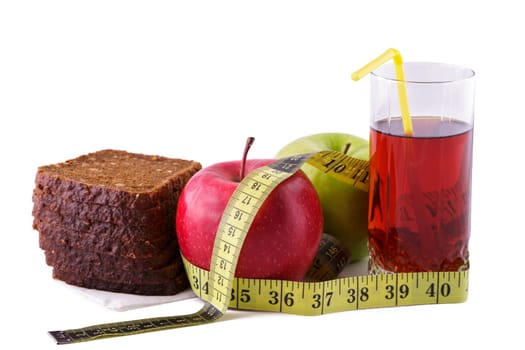 Rye bread with green and red apples and juice in a glass on a white plate with a yellow measuring tape. Diet and healthy food concept