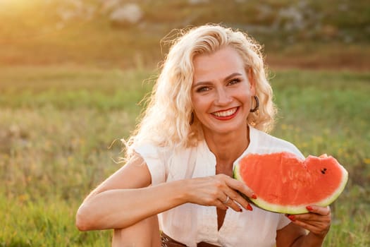 Portrait of a cute woman with a piece of watermelon in her hand in nature. Cheerful girl eating ripe red watermelon. Summer mood in nature with watermelon