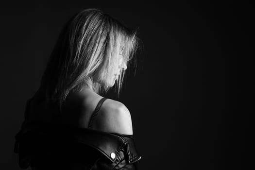 Portrait of a woman in a leather jacket and lingerie, black and white photo. Beautiful caucasian woman of nationality sensitive portrait on black background