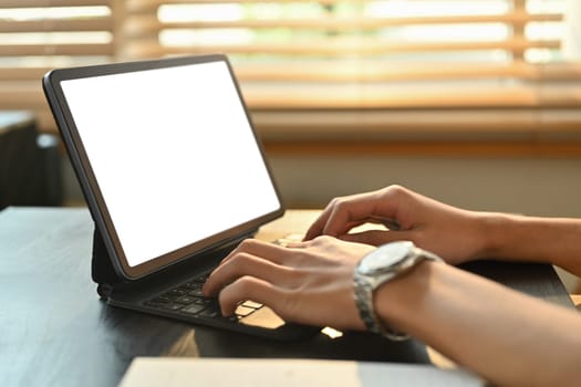 Close up view of man typing on keyboard of digital tablet, communicating online, distantly working or studying on computer at home.