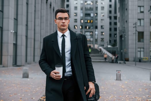 Businessman in black suit and tie is outdoors in the city.