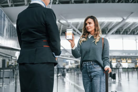 With documents. Young female tourist is in the airport at daytime.