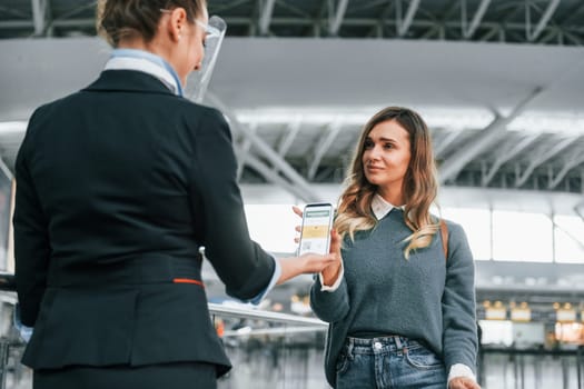 Vaccination certificate in the phone. Young female tourist is in the airport at daytime.