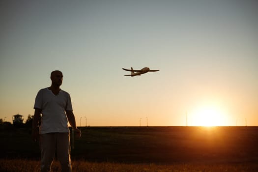 Soft focus of father and son playing toy airplane in meadow at sunset with happy emotions. Family, vacation and travel concept. At sunset in summer they launch an airplane against background sky